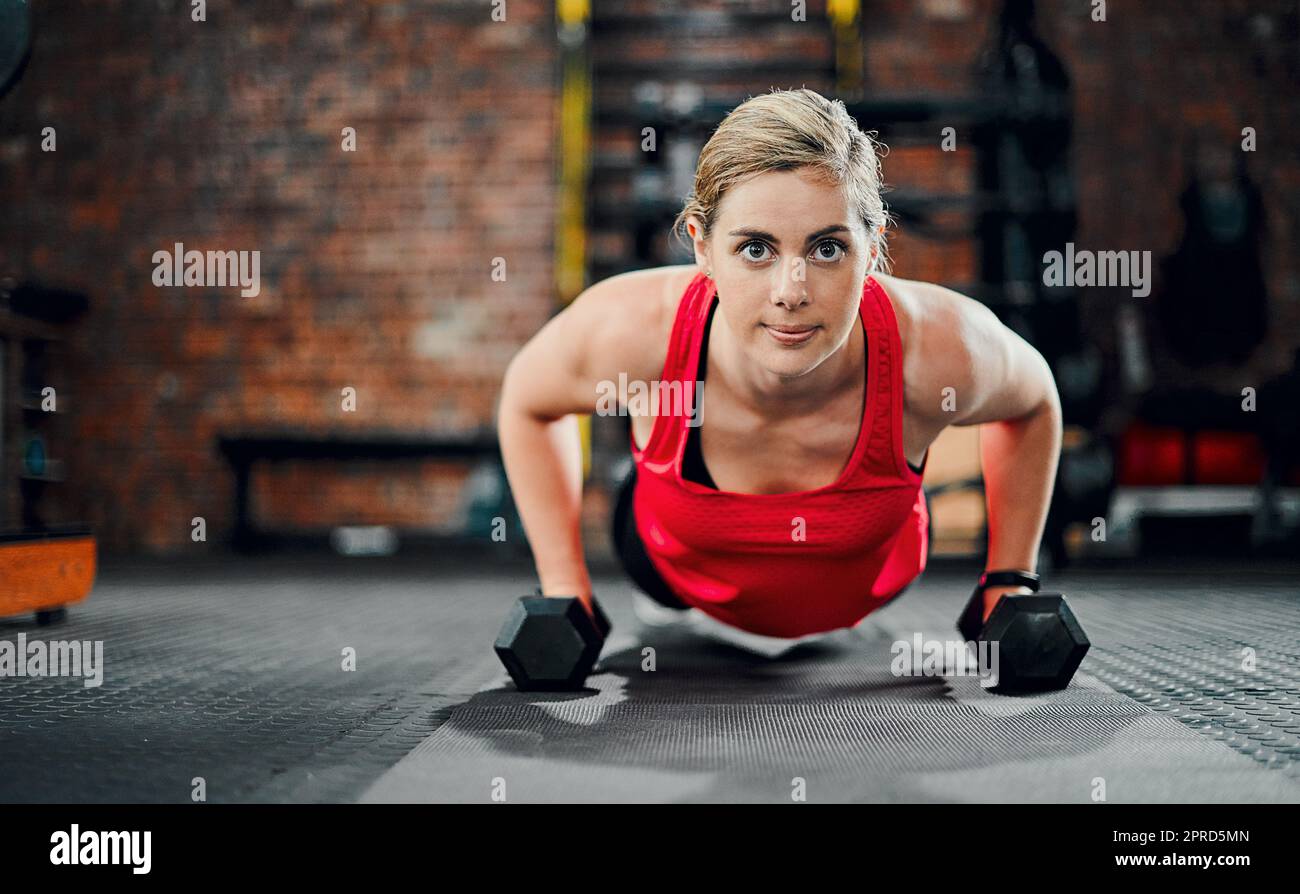 Konzentriert sich auf das Endziel. Ganzkörperportrait einer attraktiven jungen Sportlerin, die im Fitnessstudio mit Kurzhanteln trainieren soll. Stockfoto