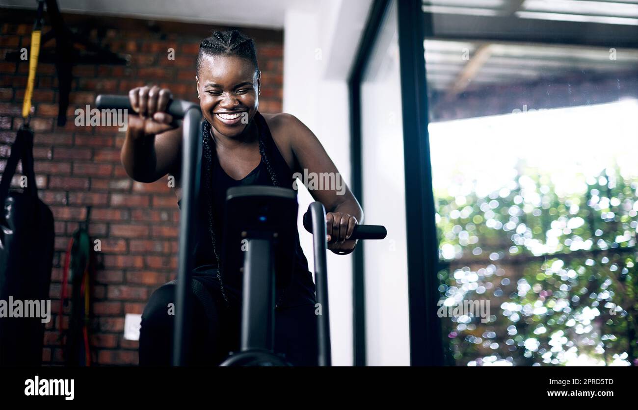 Eine attraktive junge Sportlerin, die im Fitnessstudio auf einem Crosstrainer trainieren kann. Stockfoto