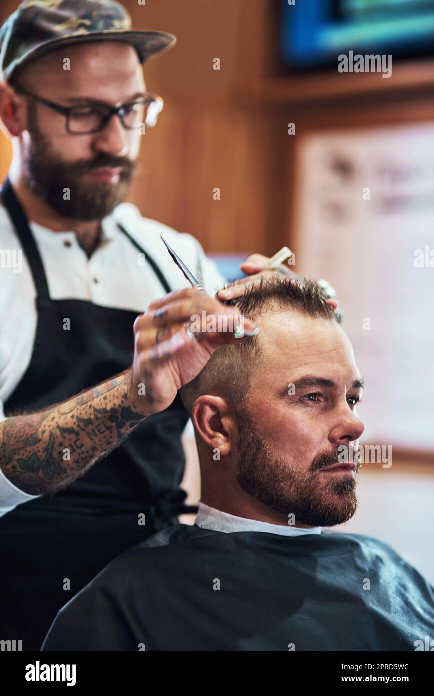 Seine Haarschnitte sind definitiv ein Schnitt über dem Rest. Ein hübscher reifer Mann bekommt einen Haarschnitt in einem Friseurladen. Stockfoto