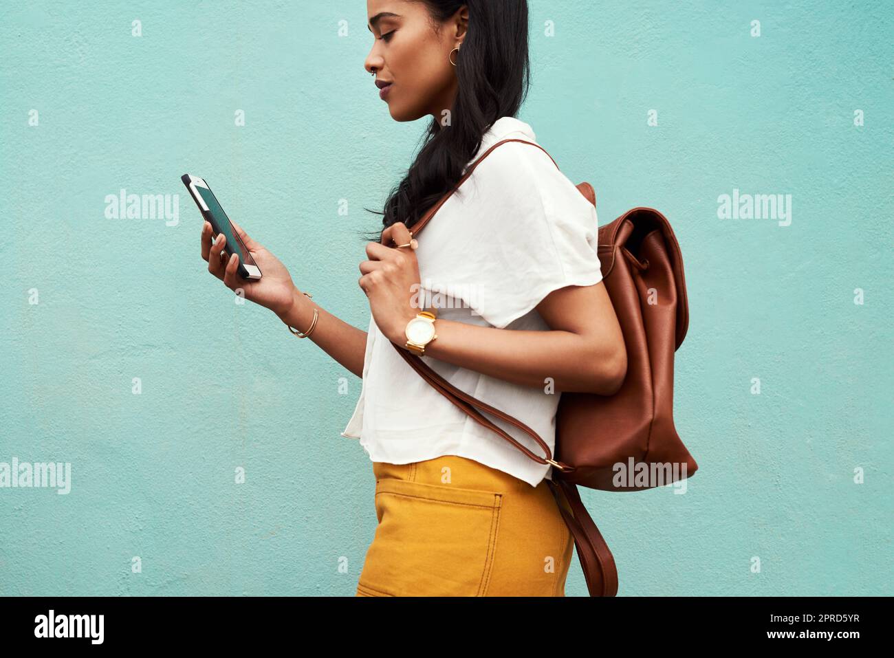Auf den Karten zu meinem nächsten Ziel. Eine unkenntliche Frau, die allein vor blauem Hintergrund steht und in der Stadt SMS schreibt. Stockfoto