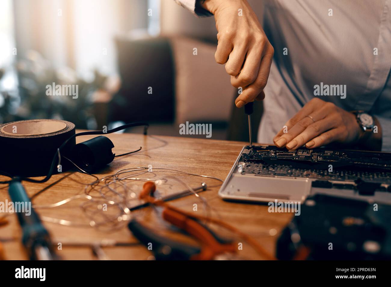 Der letzte Schliff. Eine unkenntliche Computertechnikerin repariert einen Laptop in ihrer Werkstatt. Stockfoto