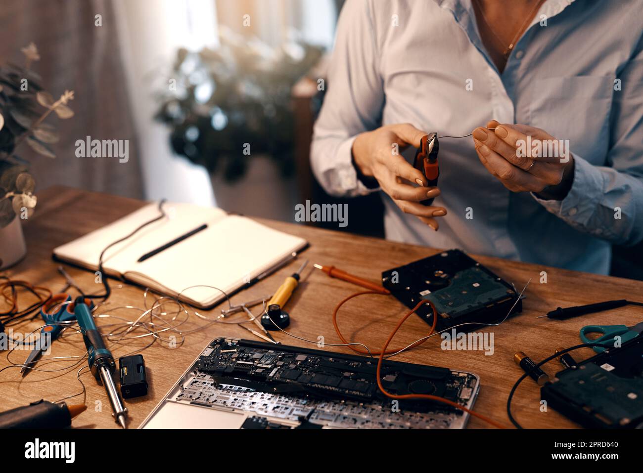 Es ist fast fertig, wieder eingesetzt zu werden. Eine unkenntliche Computertechnikerin repariert eine Festplatte in ihrer Werkstatt. Stockfoto