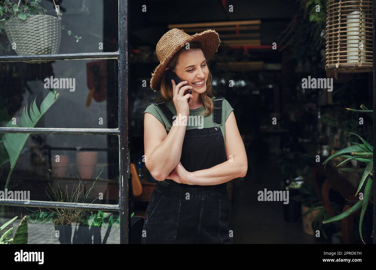 Ich mache auch Call-in-Lieferungen. Eine attraktive junge Geschäftsbesitzerin, die allein am Eingang ihrer Floristik steht, während sie an einem Telefongespräch telefoniere. Stockfoto