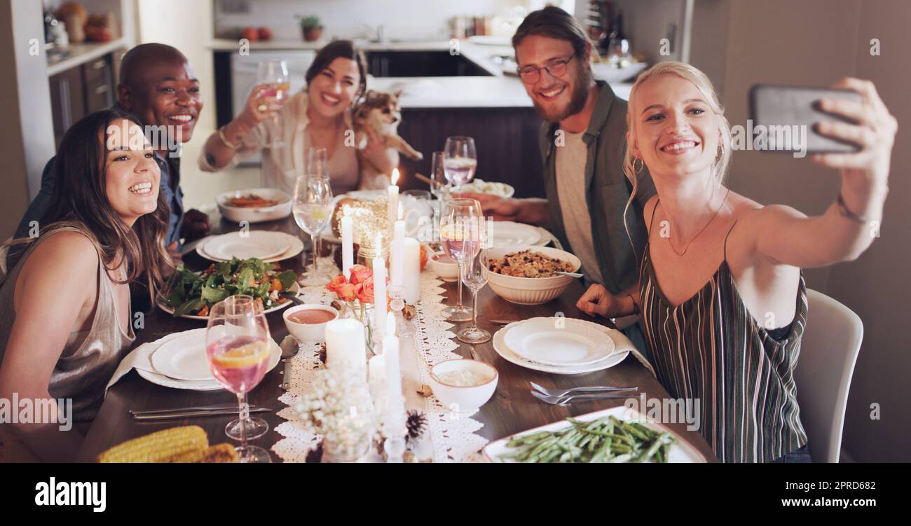 Es wäre nicht die festliche Jahreszeit ohne gute Freunde. Eine Gruppe junger Freunde, die während einer Dinner-Party zu Hause Selfies machen. Stockfoto