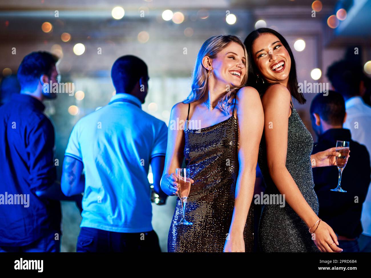 Wir sind in Flammen. Zwei fröhliche junge Frauen trinken, während sie auf der Tanzfläche eines Clubs in der Nacht tanzen. Stockfoto
