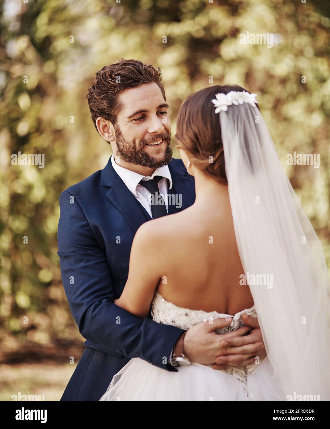 Du bist das schönste, was mir je passiert ist. Ein liebevoller junger Bräutigam, der seine Braut anlächelt, während er sie an ihrem Hochzeitstag umarmt. Stockfoto