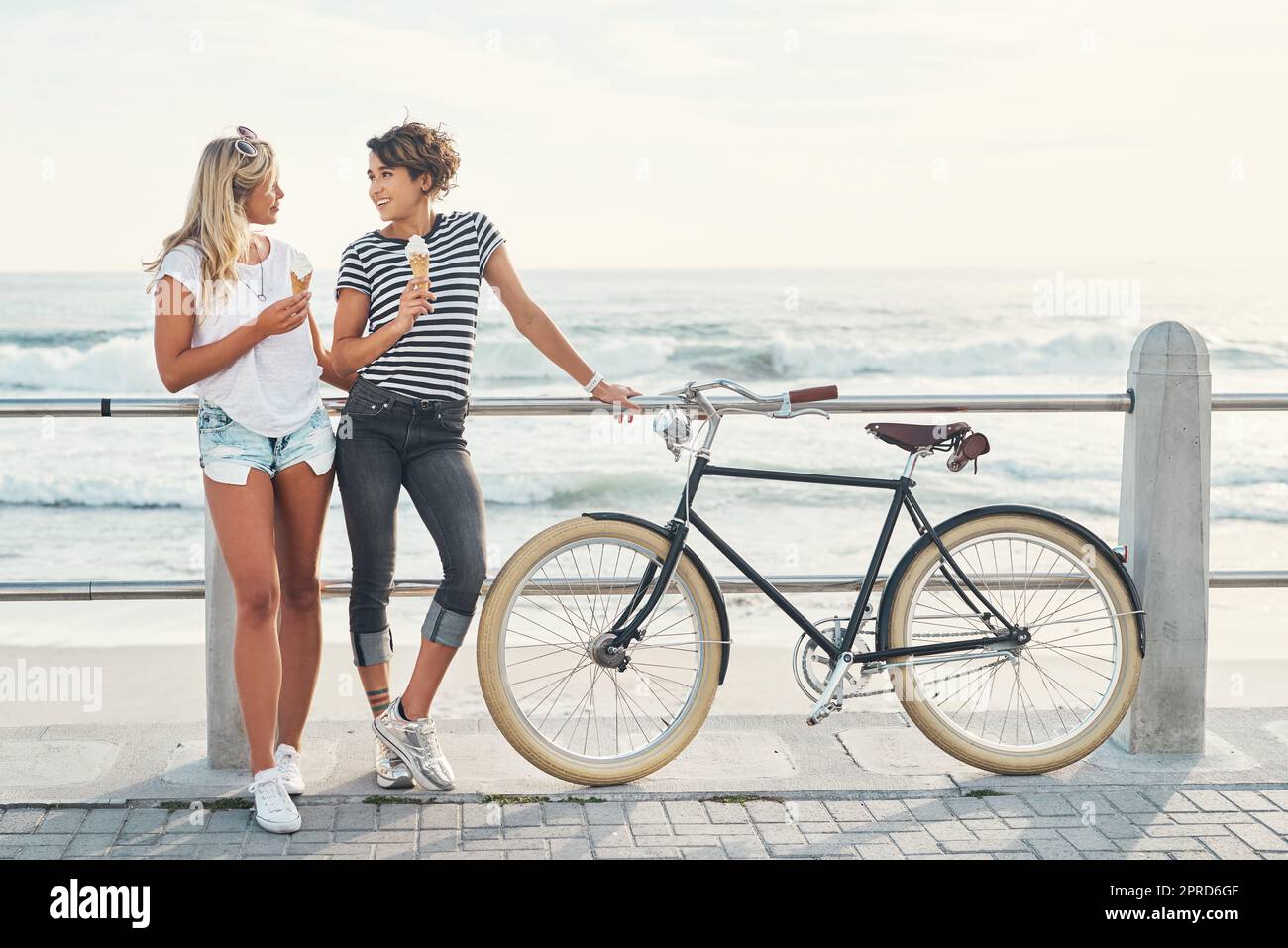 Zwei Freunde essen Eis, während sie mit dem Fahrrad auf der Promenade stehen. Stockfoto