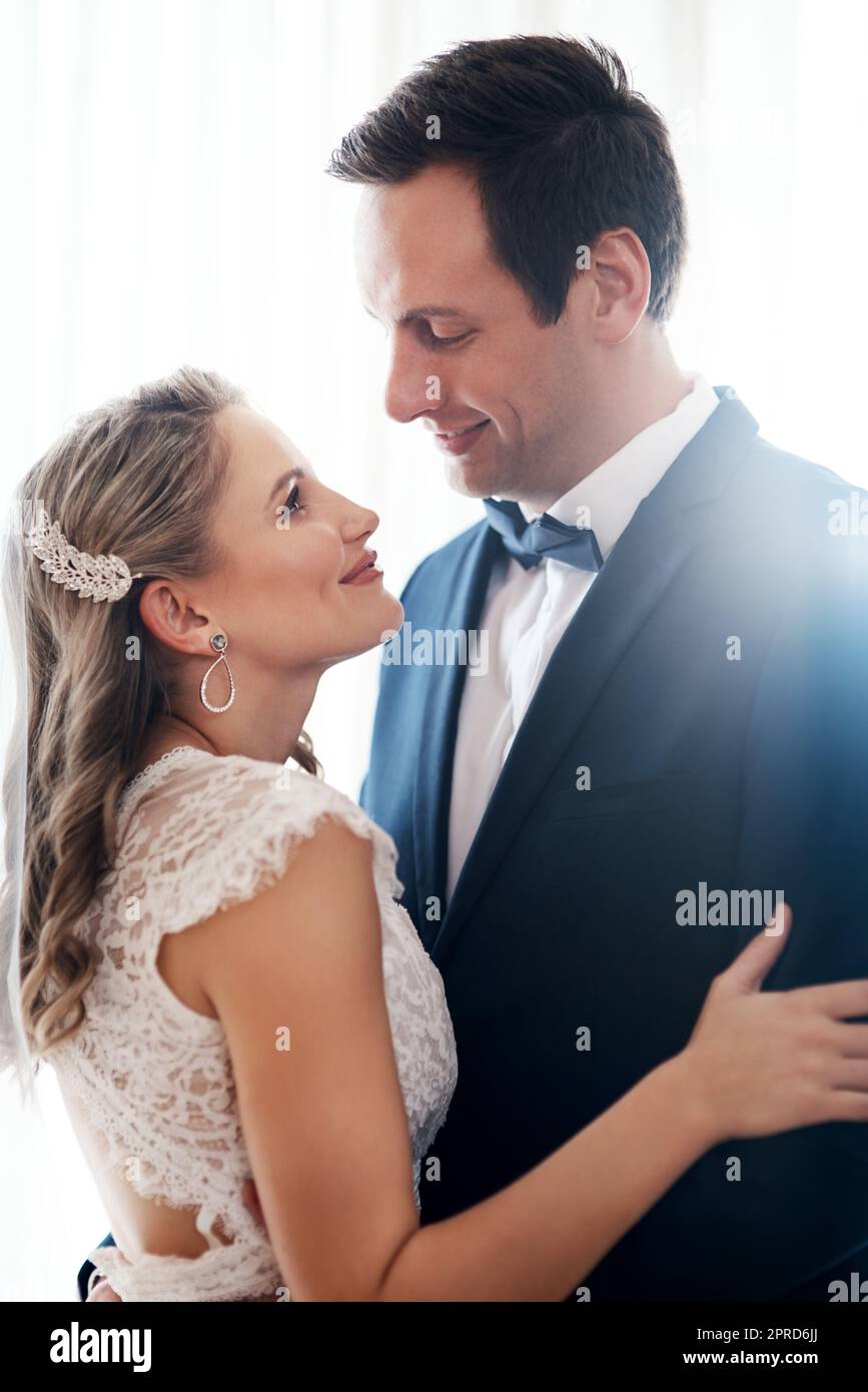 Ich konnte für immer in diese Augen schauen. Ein glückliches junges Paar, das drinnen stand und sich nach ihrer Hochzeit liebevoll hielt. Stockfoto