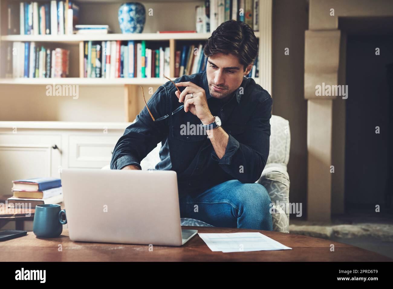 Im viel produktiver, wenn ich zu Hause arbeite. Ein hübscher junger Geschäftsmann, der einen Laptop benutzt, während er zu Hause in seinem Büro arbeitet. Stockfoto