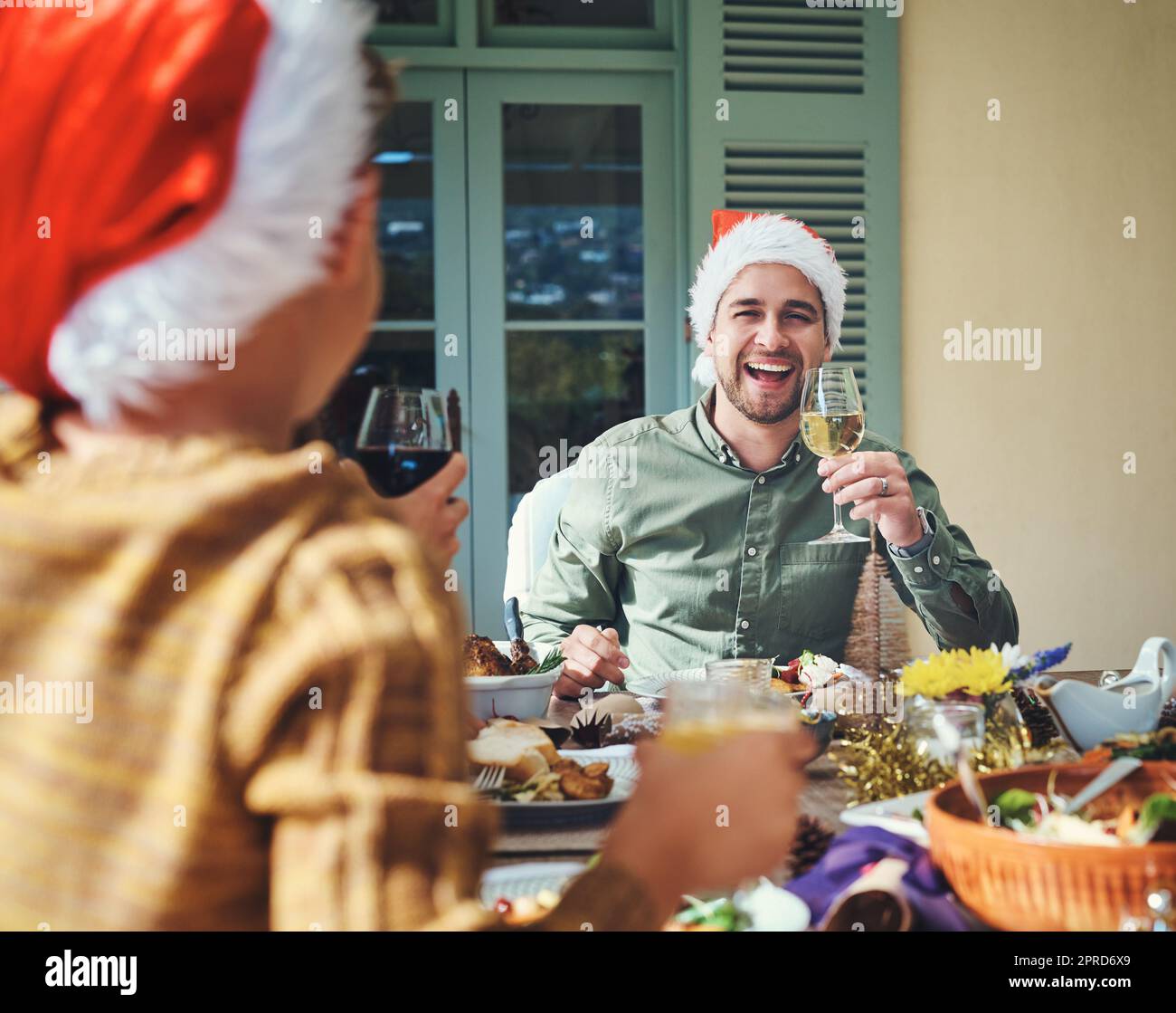 Hes fühlt sich heute sehr fröhlich. Porträt eines hübschen jungen Mannes, der sich mit Freunden und Familie auf einer Weihnachtsessen-Party vergnügt. Stockfoto