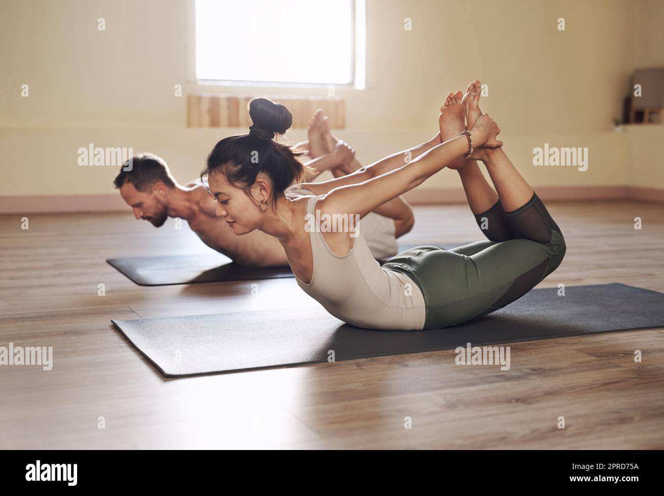 Immer gesünder und stressfrei einmal strecken zu einer Zeit. Die ganze Aufnahme von zwei jungen Menschen, die in einem Yoga-Kurs zusammen arbeiten. Stockfoto