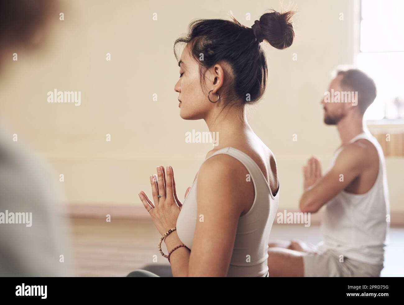 Yoga hilft uns dabei, unseren Geist zu beruhigen. Eine Gruppe junger Menschen meditiert und praktiziert gemeinsam Yoga in einem Yoga-Studio. Stockfoto