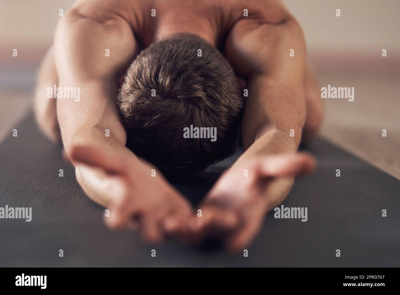 Lass die Zen übernehmen. Ein unkennbarer Mann, der sich ausdehnt und in Innenräumen Yoga praktiziert. Stockfoto