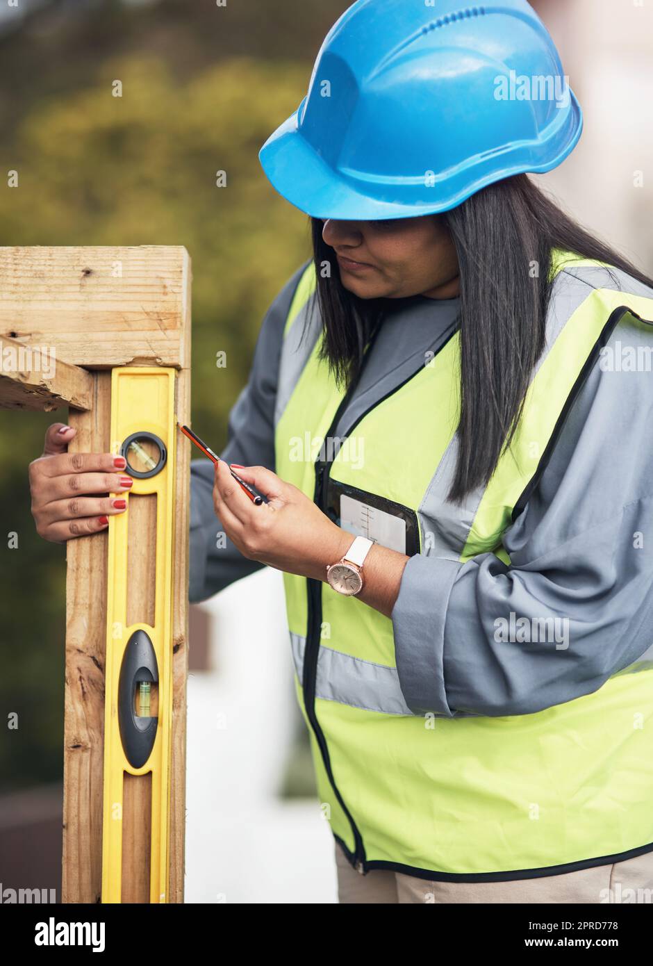 Markieren Sie jeden Punkt mit Präzision. Eine attraktive junge Bauarbeiterin, die vor Ort arbeitet. Stockfoto