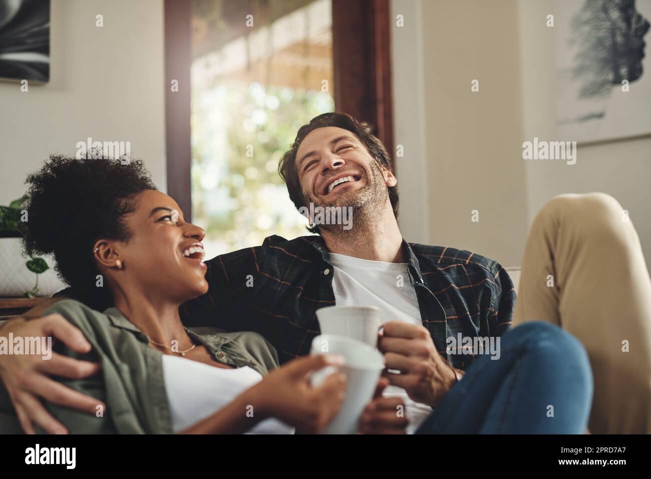 Kaffee und Gespräche. Ein glückliches junges Paar, das Kaffee trinkt und zu Hause eine schöne Zeit miteinander verbringt. Stockfoto