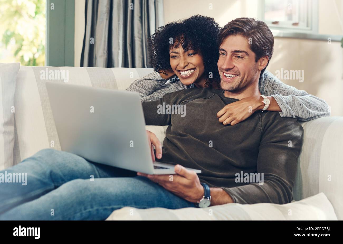 Es gibt so viele lustige Videos online zu sehen. Ein liebevolles junges Paar mit einem Laptop zusammen, während in ihrem Wohnzimmer zu Hause entspannen. Stockfoto