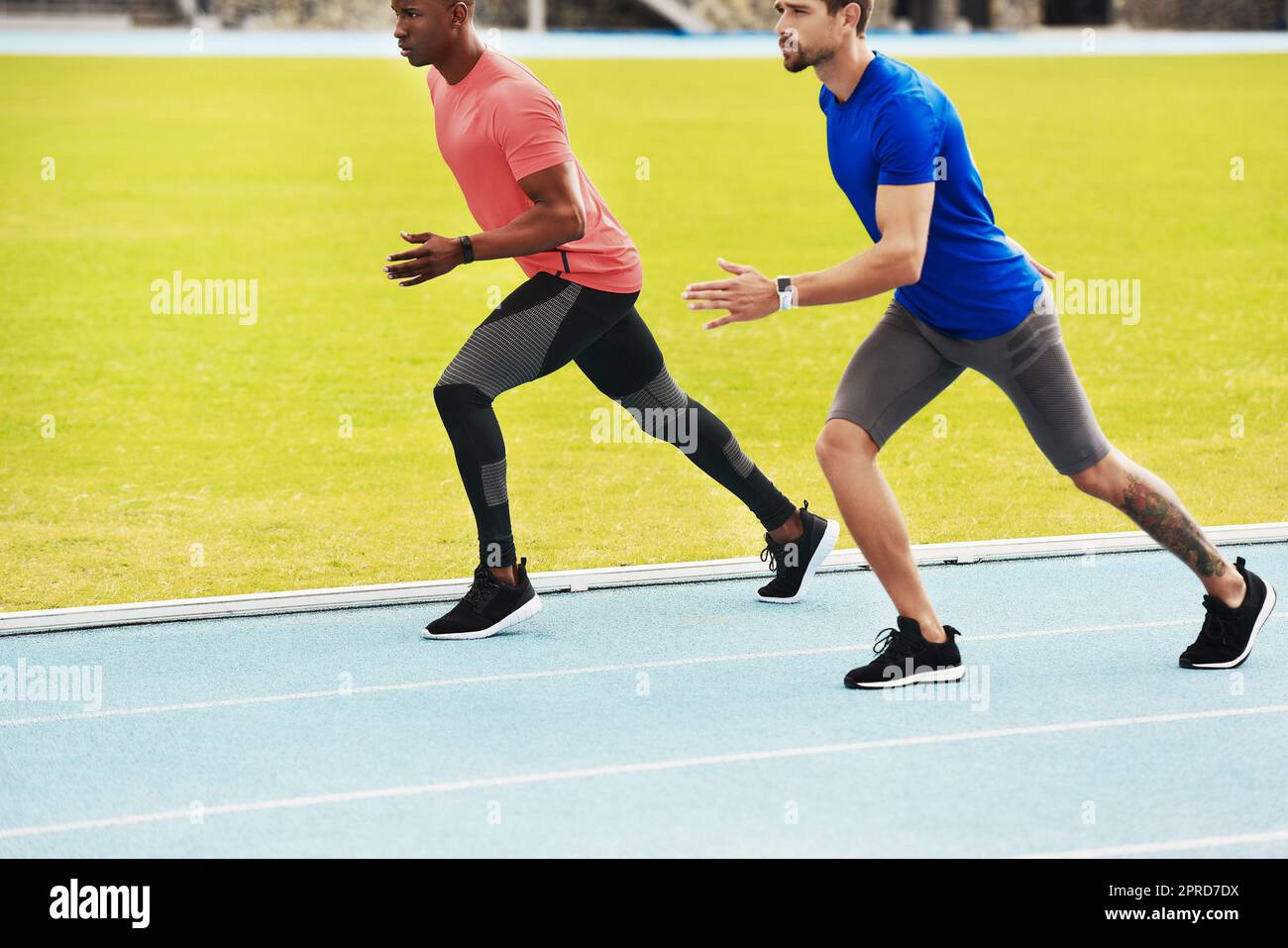 Zwei hübsche junge Athleten laufen auf der Strecke. Stockfoto
