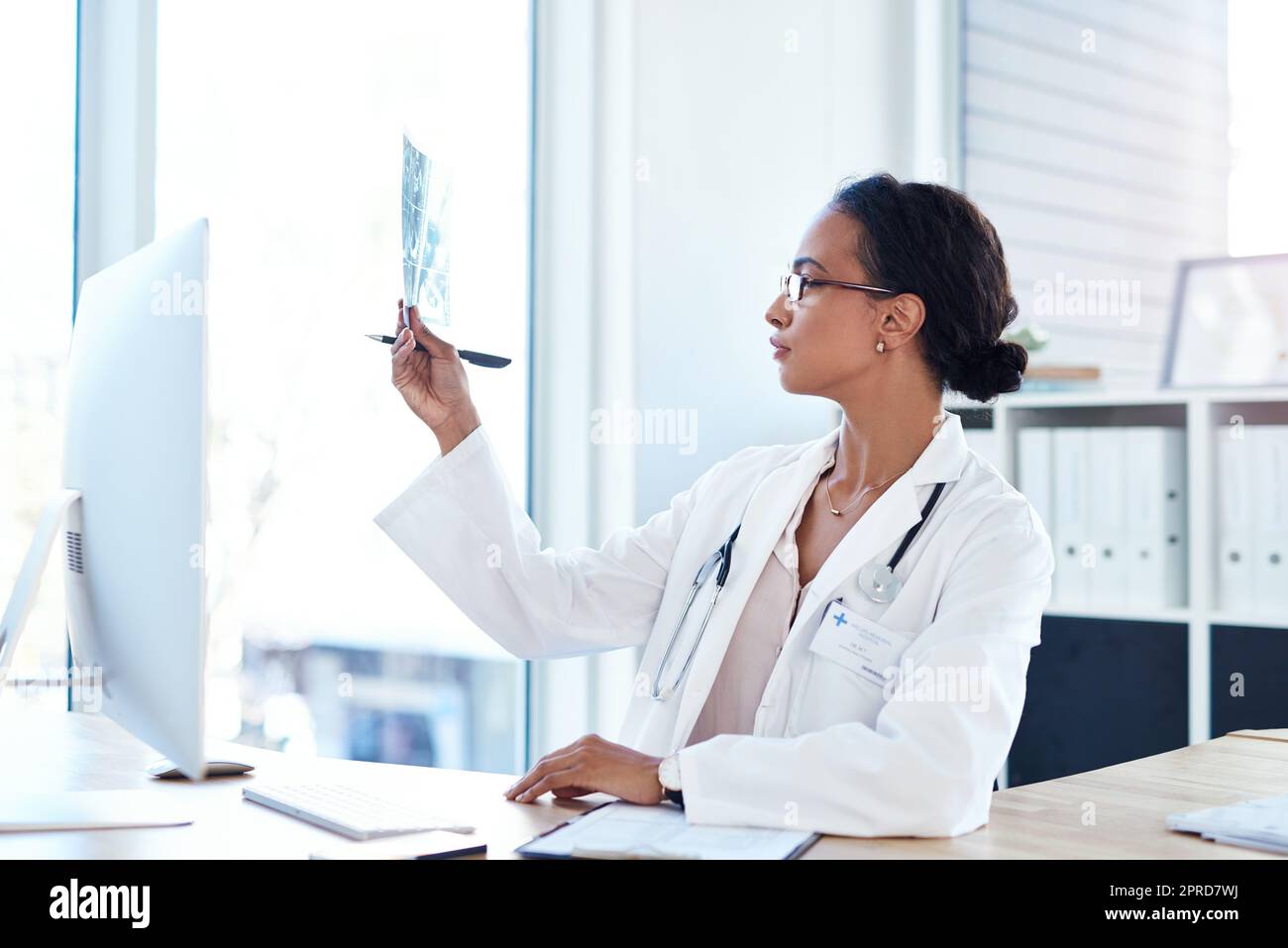 Eine junge Ärztin, die die Ergebnisse eines Röntgenstrahls in ihrem Sprechzimmer liest. Stockfoto