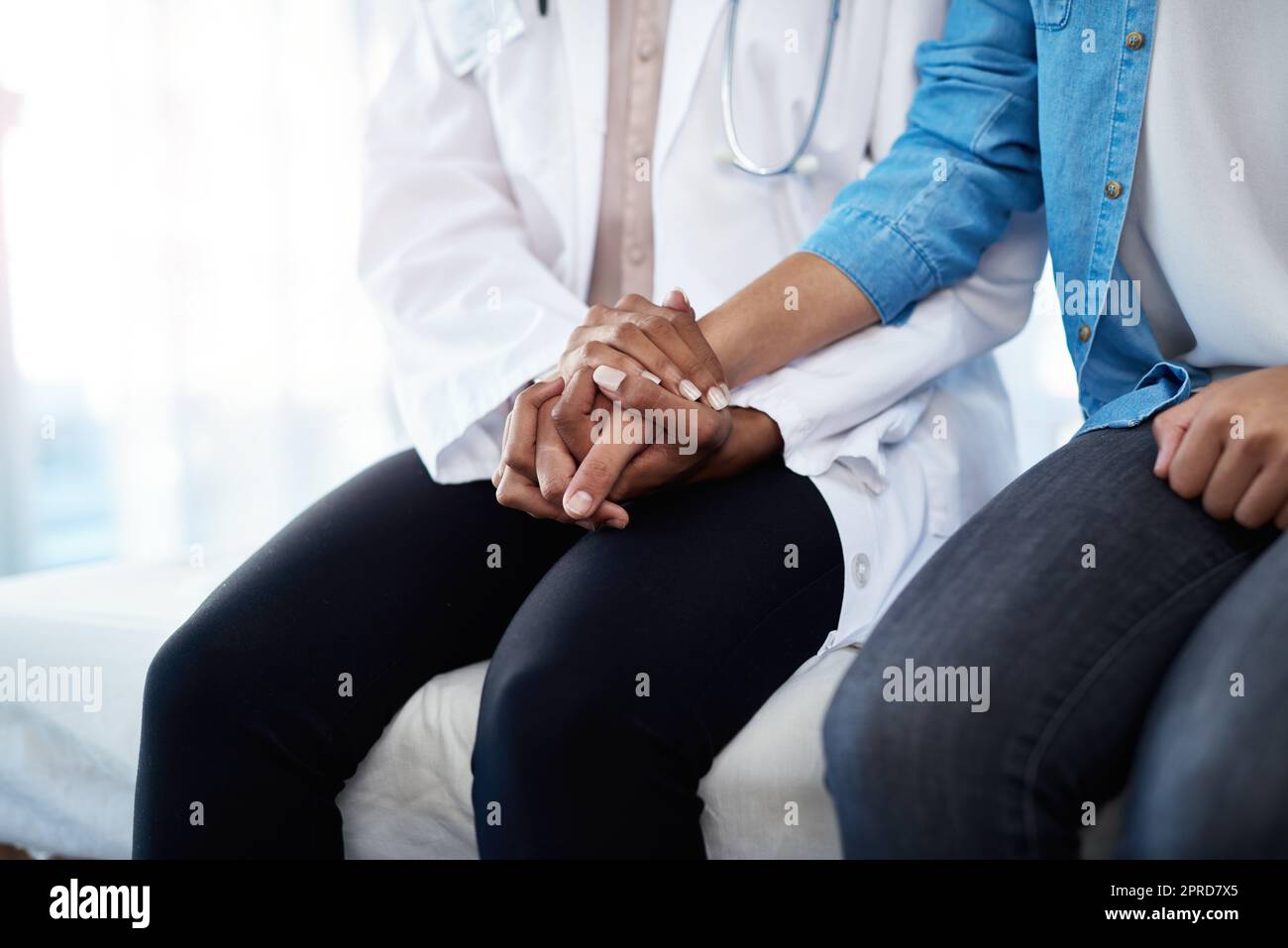 Mitgefühl kann sehr heilen. Ein Arzt hält sich in ihrem Sprechzimmer mit einer Patientin an die Hand. Stockfoto