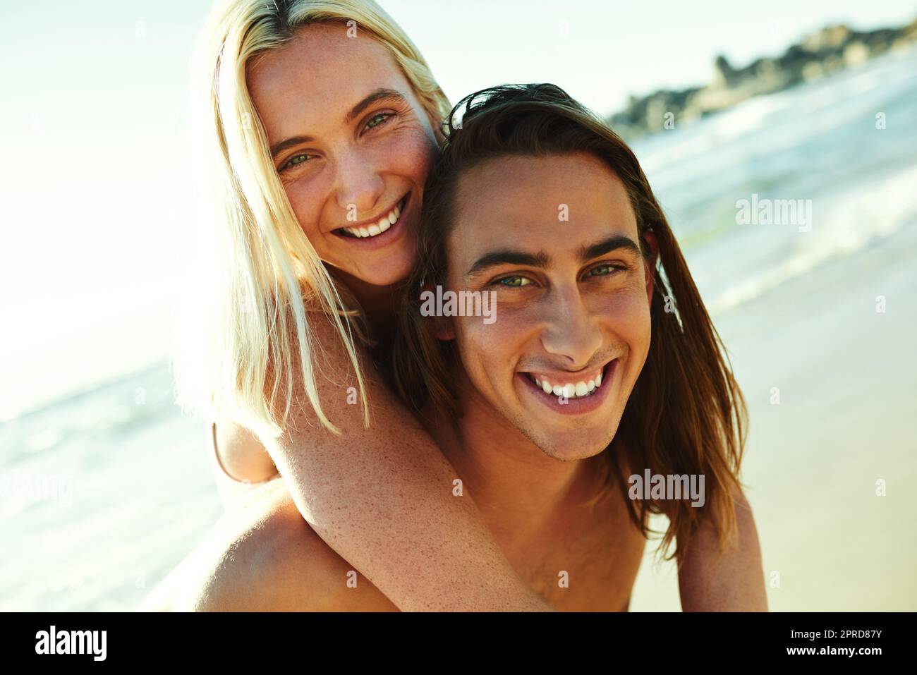 Diese Liebsten sind total verliebt. Porträt eines jungen Mannes, der seiner Freundin eine Huckepack-Fahrt am Strand gibt. Stockfoto