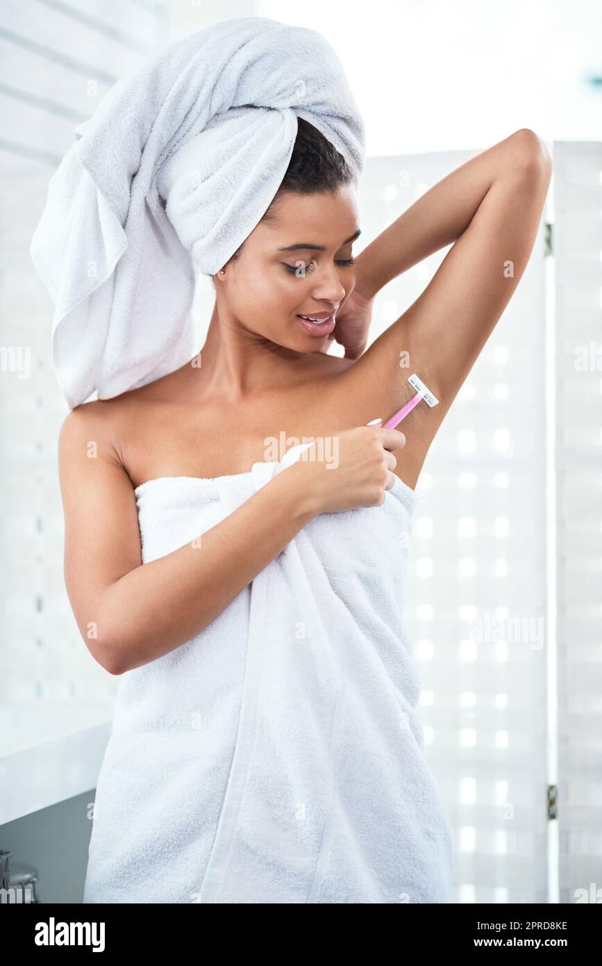 Loszuwerden unerwünschte Haare. Eine attraktive junge Frau rasieren ihre Achselhöhlen mit einem Rasiermesser im Badezimmer. Stockfoto