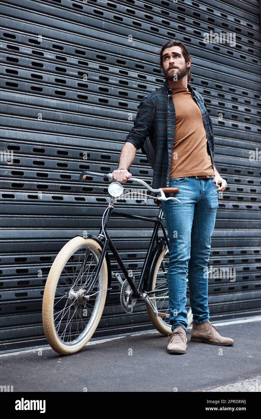 Moderne Männer Rollen in dieser Art von Rädern herum. Ganzkörperaufnahme eines hübschen jungen Mannes, der neben seinem Fahrrad im Freien posiert. Stockfoto