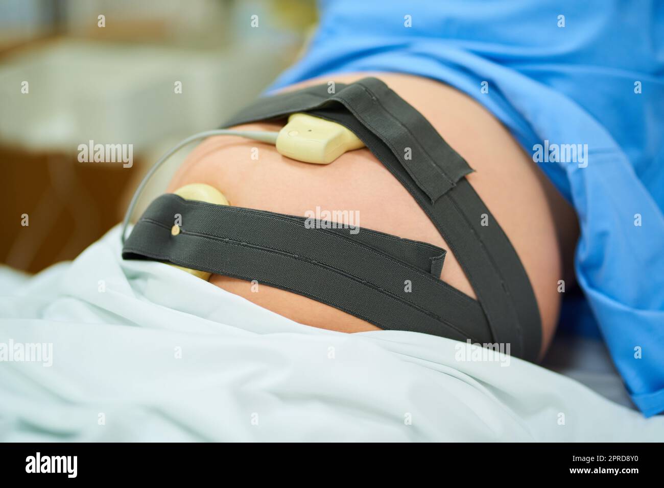 Moderne Technologie hat dazu beigetragen, den gesamten Geburtsvorgang problemlos zu überwachen. Eine unkenntliche Schwangere liegt in ihrem Krankenhausbett an ihrem Fälligkeitstermin. Stockfoto