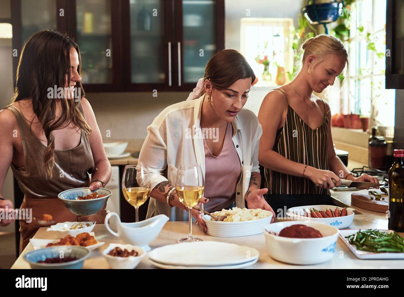 Eine Gruppe fröhlicher junger Freunde bereitet tagsüber gemeinsam zu Hause in der Küche zu. Stockfoto