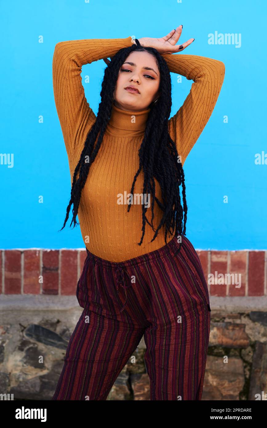 Ich kann das alles alleine machen. Eine schöne junge Frau, die vor einer blauen Wand posiert. Stockfoto