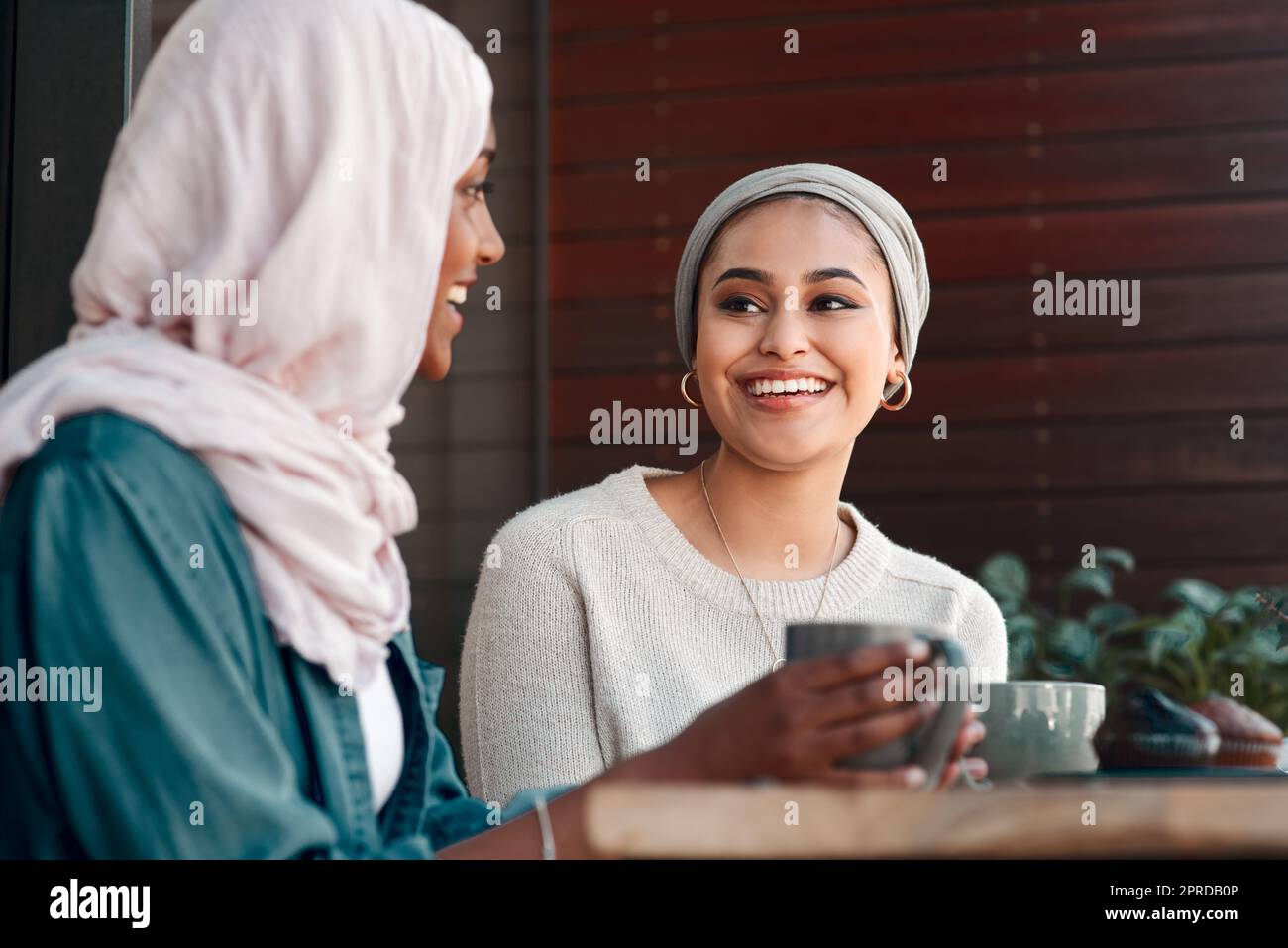 Es ist wirklich schön, mit Ihnen aufzuholen. Zwei liebevolle junge Freundinnen, die einen Chat in einem Café, während in Hijab gekleidet. Stockfoto
