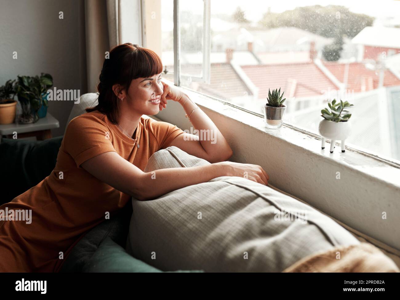 Es ist ein schöner Tag draußen. Eine attraktive junge Frau, die sich zu Hause auf dem Sofa entspannt. Stockfoto