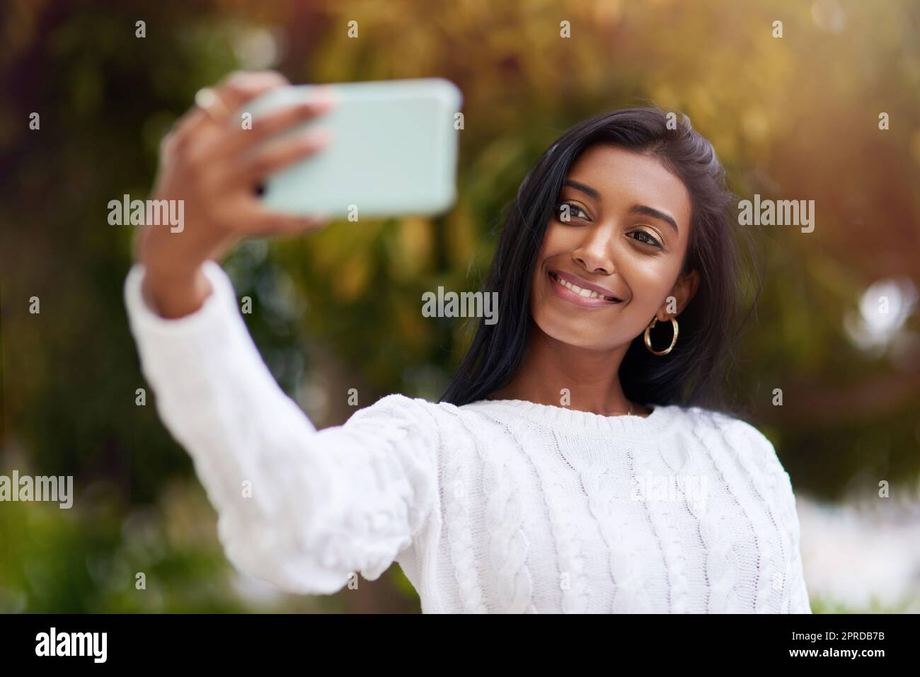 Schieß los. und verändern Sie die Welt mit Ihrem Lächeln. Eine junge Frau, die ein Selfie während draußen in der Stadt. Stockfoto