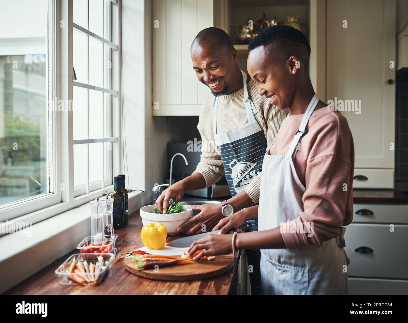Was du da drüben hast. Ein liebevolles junges Paar bereitet das Abendessen in ihrer Küche vor. Stockfoto