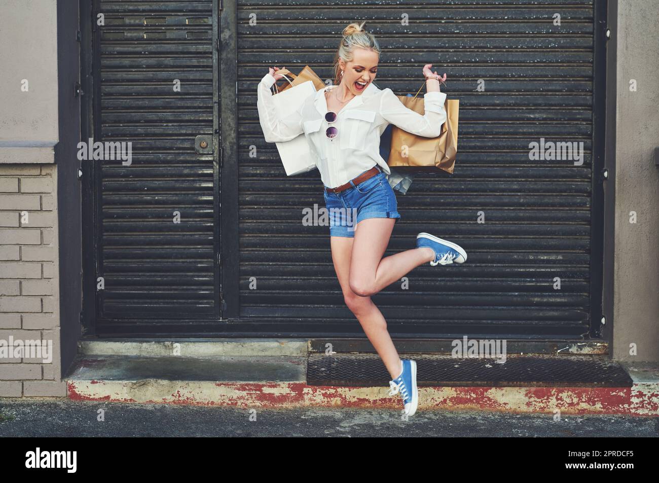 Einkaufen bringt ihr so viel Freiheit. Aufnahme einer attraktiven jungen Frau in voller Länge, die vor dem Hintergrund der Stadt vor Freude mit ihren Einkaufstaschen hüpft. Stockfoto