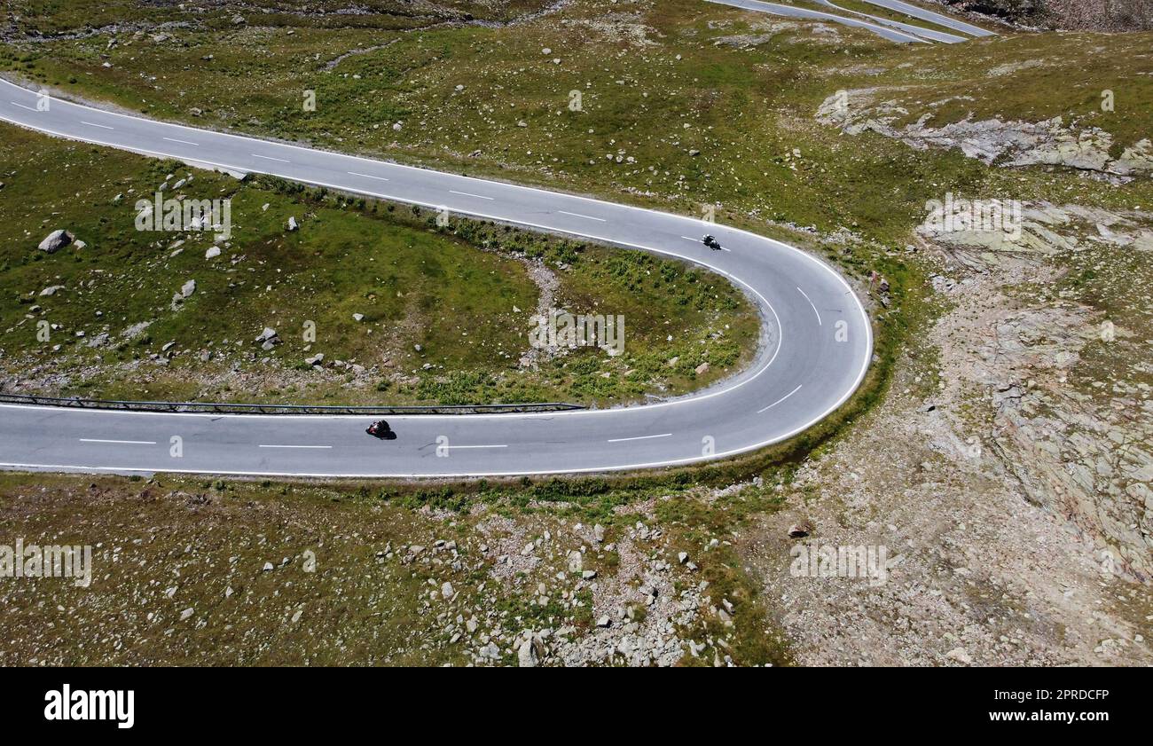 Luftdrohnenaufnahme von engen Kurven mit Motorradfahrer in den Bergen Stockfoto