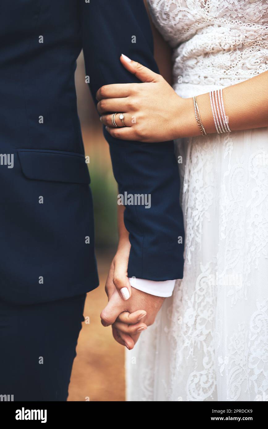 Hand in Hand durch alles für immer. Ein unbekanntes, frisch verheiratetes Paar, das die Hände hält und an ihrem Hochzeitstag zusammenläuft. Stockfoto