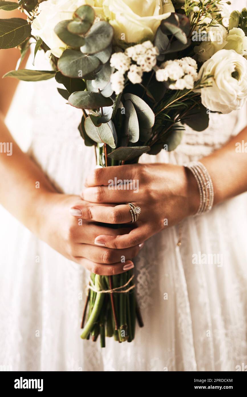 Der perfekte Blumenstrauß ergänzt immer Ihr Hochzeitskleid. Eine unkenntliche Braut hält einen Blumenstrauß an ihrem Hochzeitstag. Stockfoto