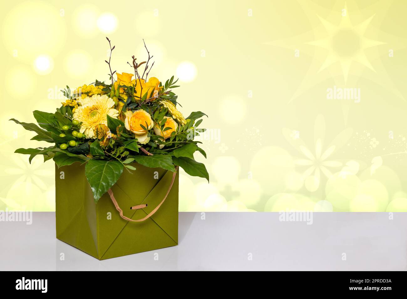 Abschluss eines wunderschönen Straußes gelber Blumen in einer dekorativen grünen Geschenkbox auf einem hellen Tisch vor einem abstrakten Frühlingshintergrund. Makro. Raum für Design. Kartenkonzept. Stockfoto