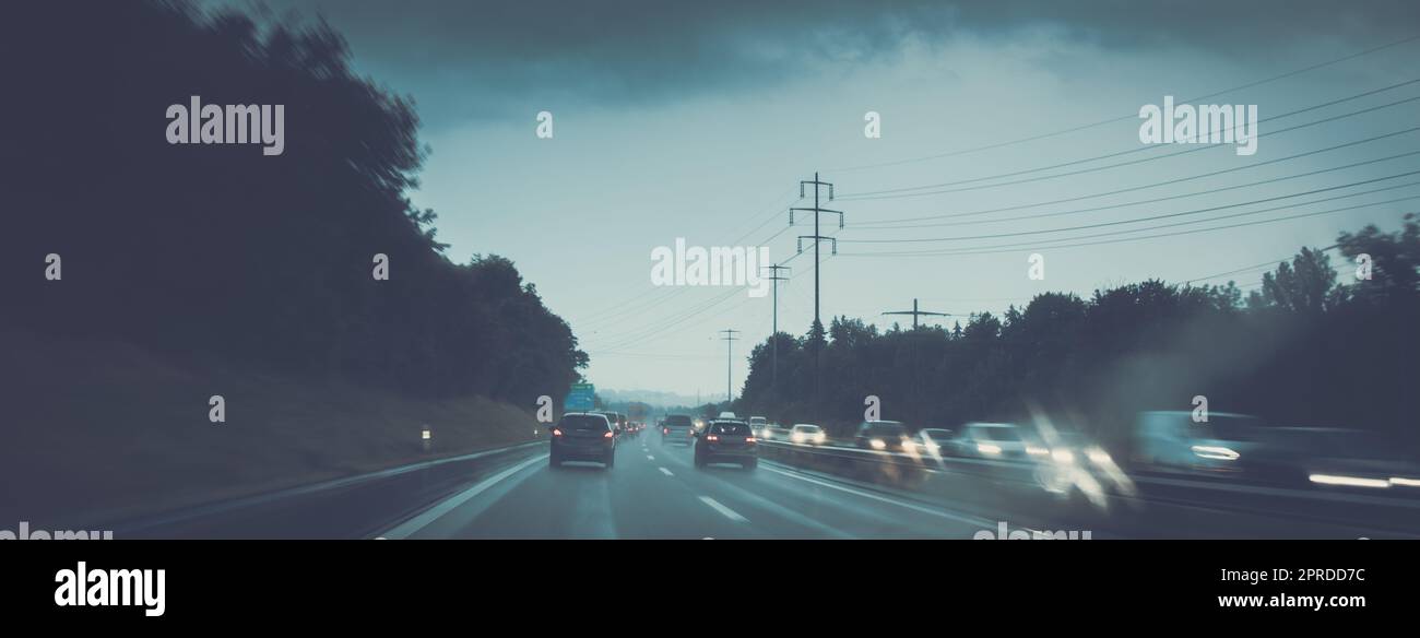 Autos auf einer Autobahn in der regnerischen Dämmerung (flaches, farbiges Bild des Freiheitsgrads) Stockfoto