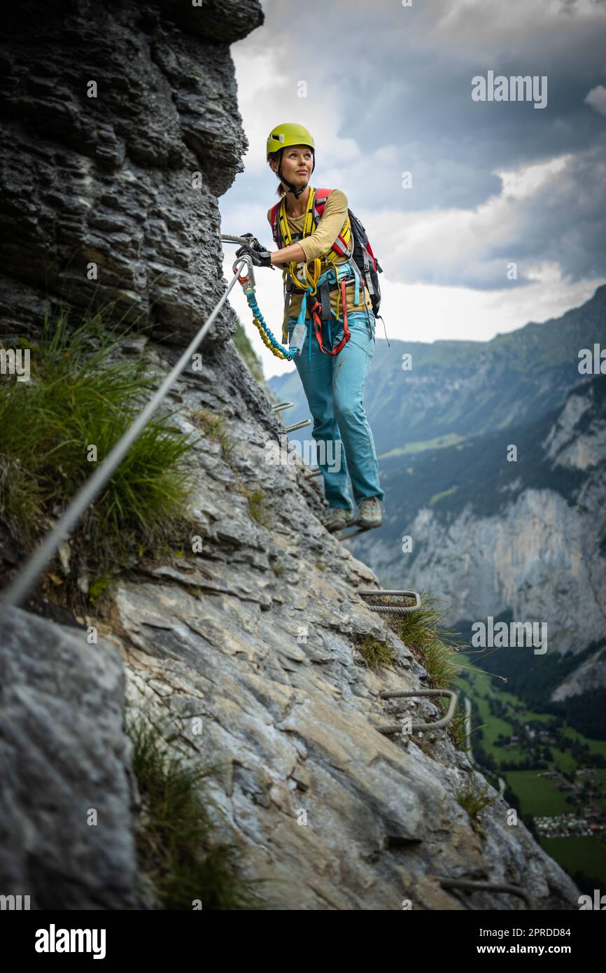 Hübschen, weiblichen Kletterer am Klettersteig - Klettern auf einem Felsen in den Schweizer Alpen Stockfoto