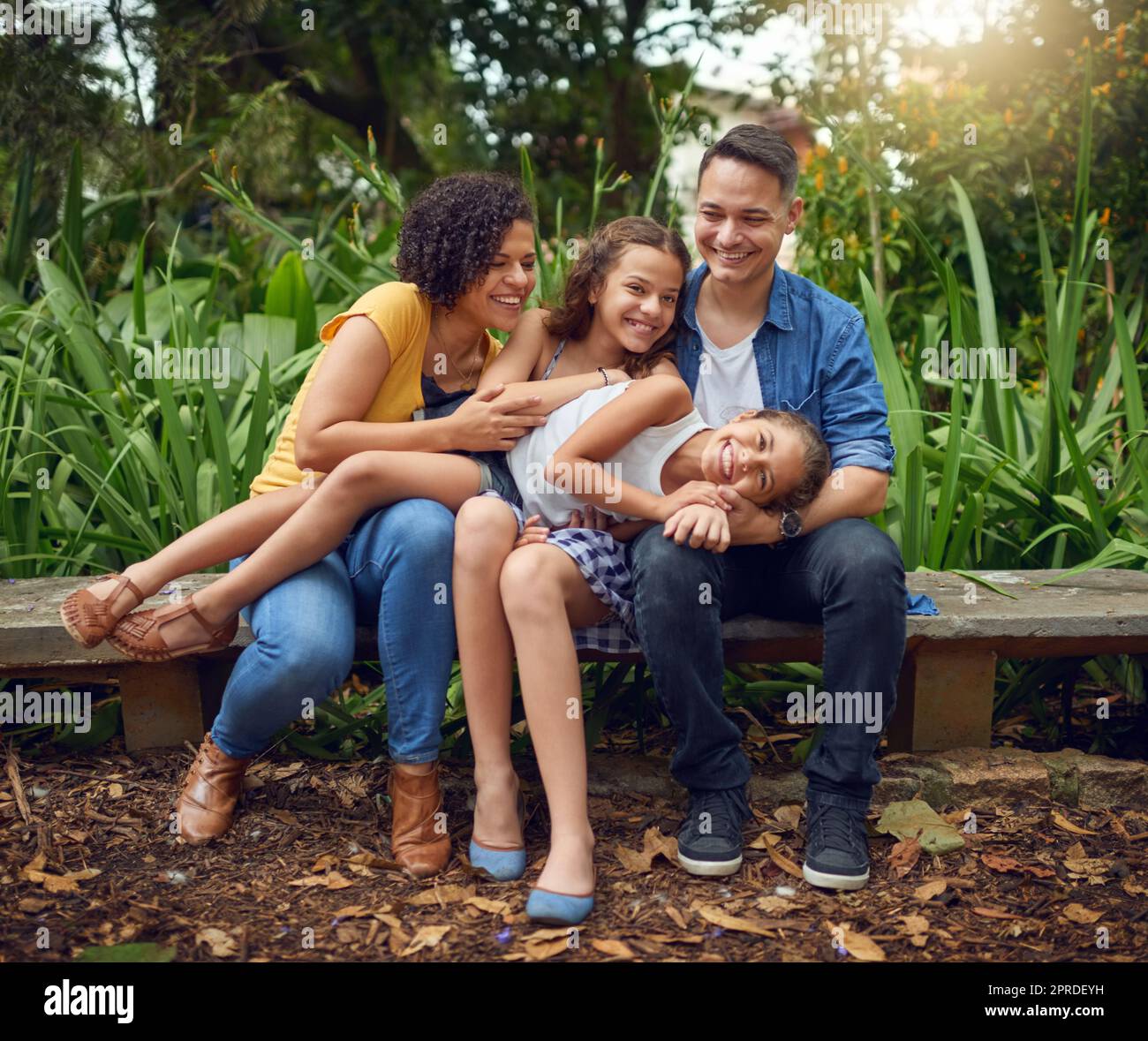 Unbezahlbare Momente für die Familie. Die ganze Aufnahme einer glücklichen Familie, die einige Zeit zusammen auf einer Bank im Park verbringt. Stockfoto