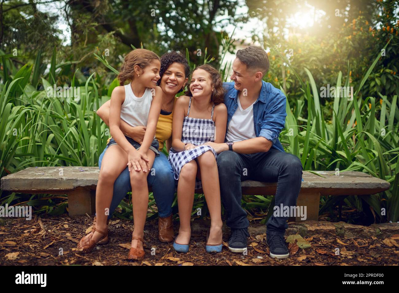 Familienzeiten sind Zeiten voller Lachen. Die ganze Aufnahme einer glücklichen Familie, die einige Zeit zusammen auf einer Bank im Park verbringt. Stockfoto