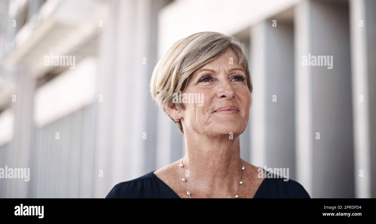 Um groß zu gehen, hast du große Schritte zu machen. Eine reife Geschäftsfrau, die durch die Stadt läuft. Stockfoto