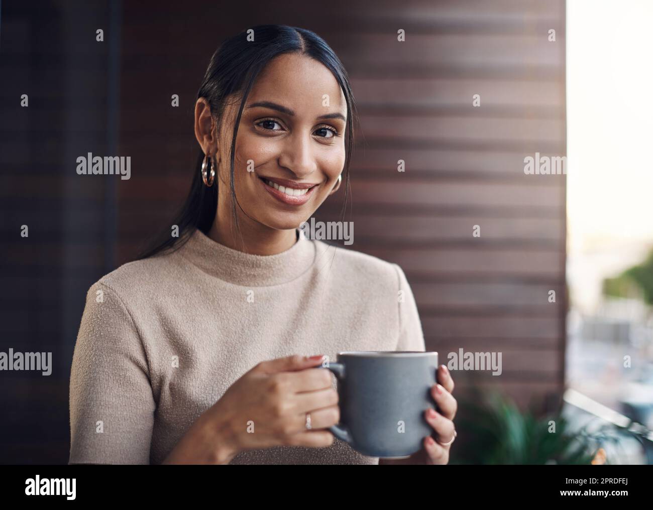 Was ist ein Arbeitstag ohne Kaffee. Ein Porträt einer attraktiven jungen Geschäftsfrau, die ihren Kaffee trinkt, während sie im Büro arbeitet. Stockfoto