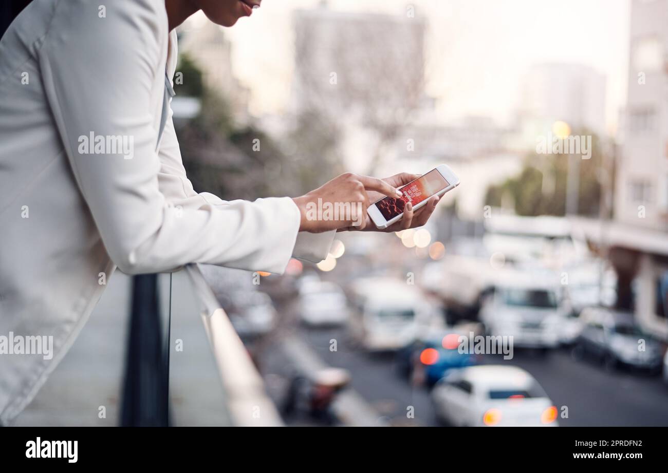 Telefon in den Händen einer Frau für Kommunikation, Networking und Anrufe, während Sie auf einem Balkon über einer städtischen Straße stehen. Ein professioneller Mitarbeiter macht eine Pause und surft mit einer mobilen App Stockfoto