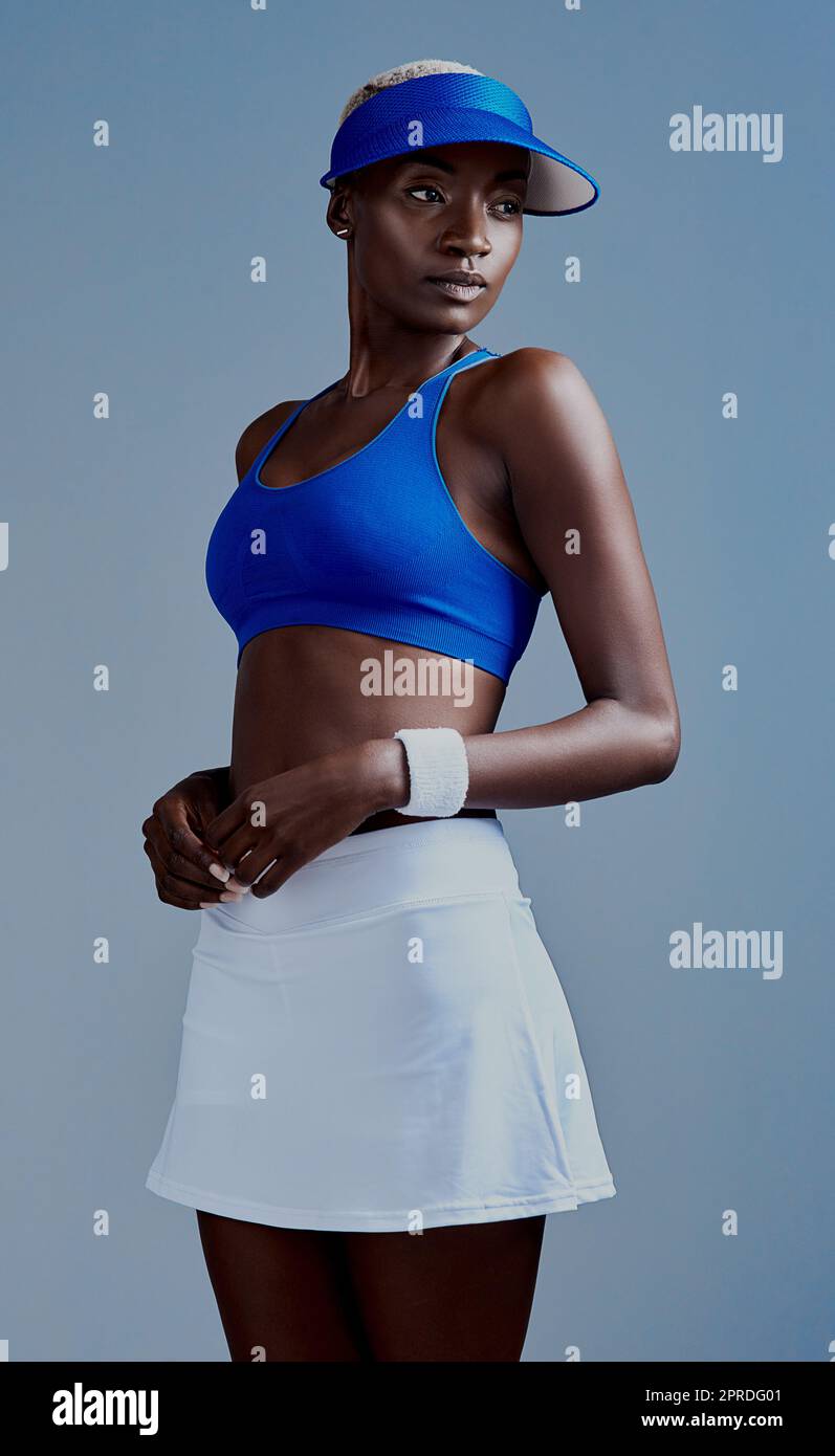Dress up und zeigen sich. Studioaufnahme einer sportlichen jungen Frau, die eine Tennisuniform trägt und vor einem grauen Hintergrund posiert. Stockfoto