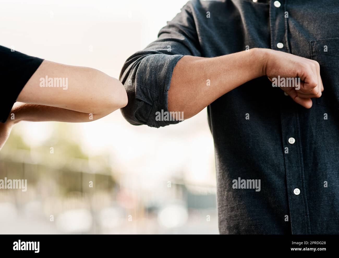 Eine einfache Geste könnte Sie sicher halten. Ein unkenntlich Mann und eine Frau stoßen Ellbogen im Freien. Stockfoto
