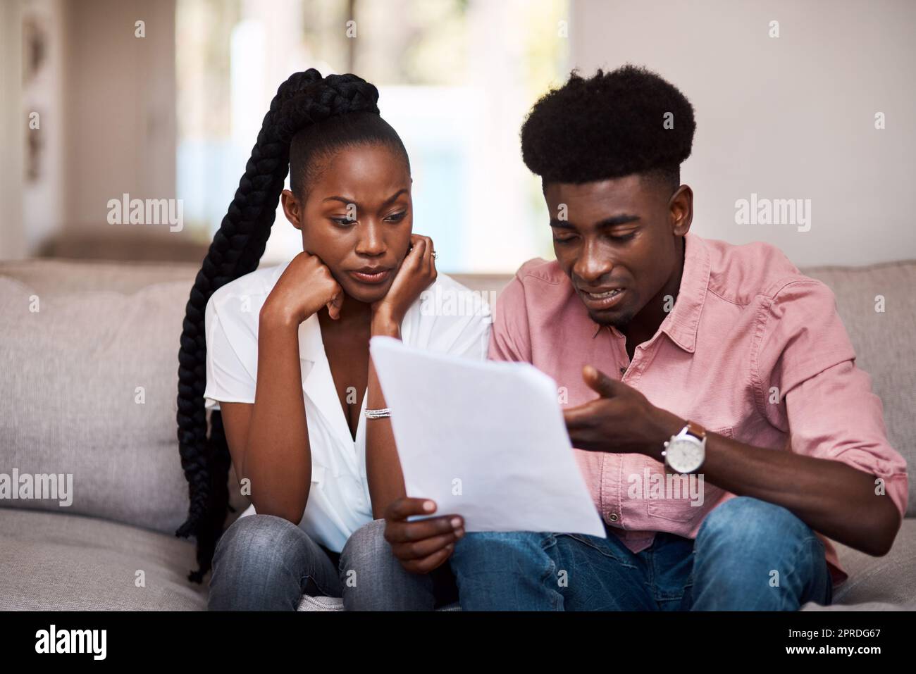 Wie werden wir uns das leisten? Ein junges Paar, das gestresst aussieht, während wir zu Hause über Papierkram gehen. Stockfoto