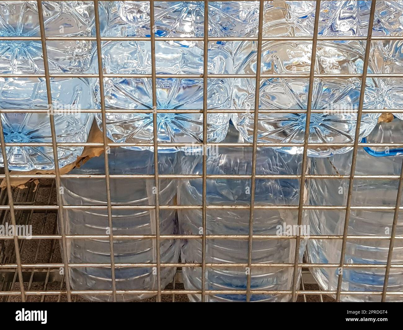 Lagerung und Transport von großen Plastikflaschen für sauberes Trinkwasser in einem Behälter mit Metallrost, Nahaufnahme Stockfoto