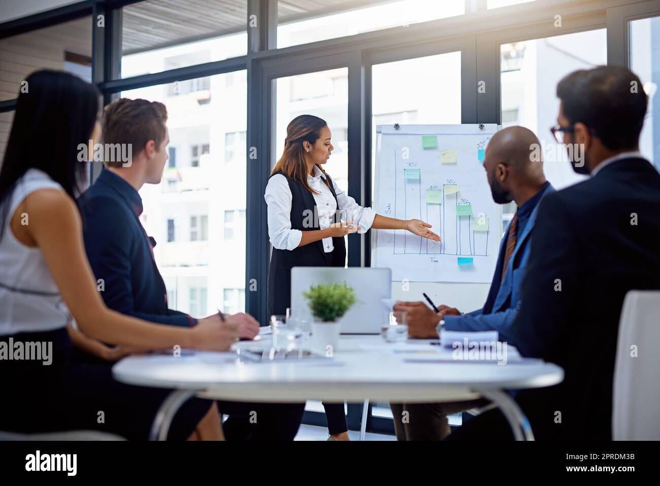 Shes bekam jedermanns Aufmerksamkeit. Eine junge Geschäftsfrau, die ihren Kollegen in einem modernen Büro eine Demonstration auf einem Whiteboard gab. Stockfoto